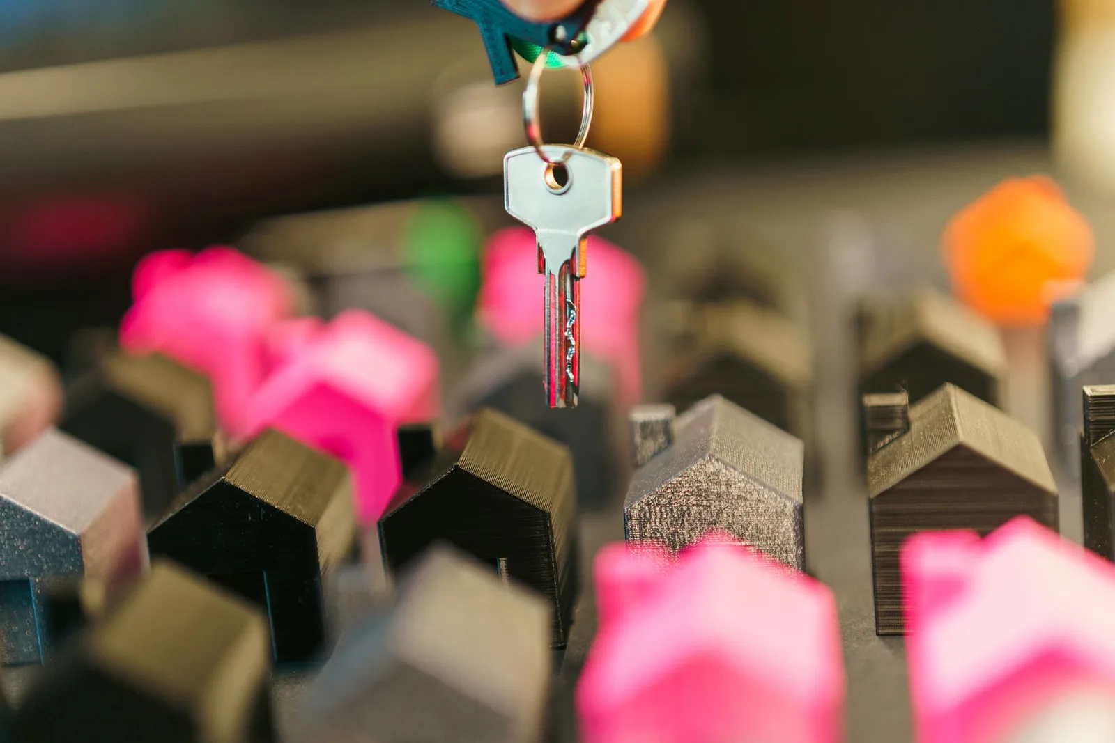 A hand holding a house key over miniature houses, symbolizing streamlined real estate automation and efficient property trans